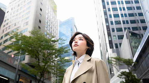 都会の空を眺める若い女性