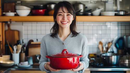 キッチンで赤い鍋を持つ笑顔の女性