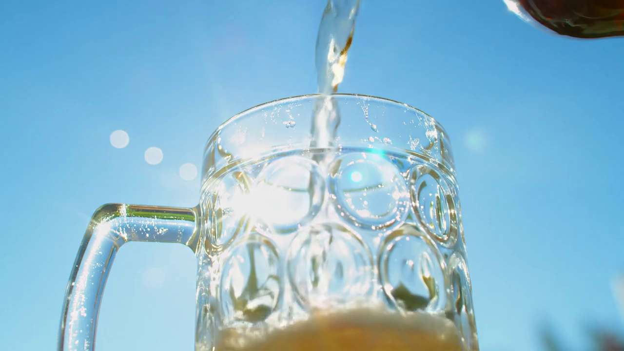 青空の下で注ぐビールの映像